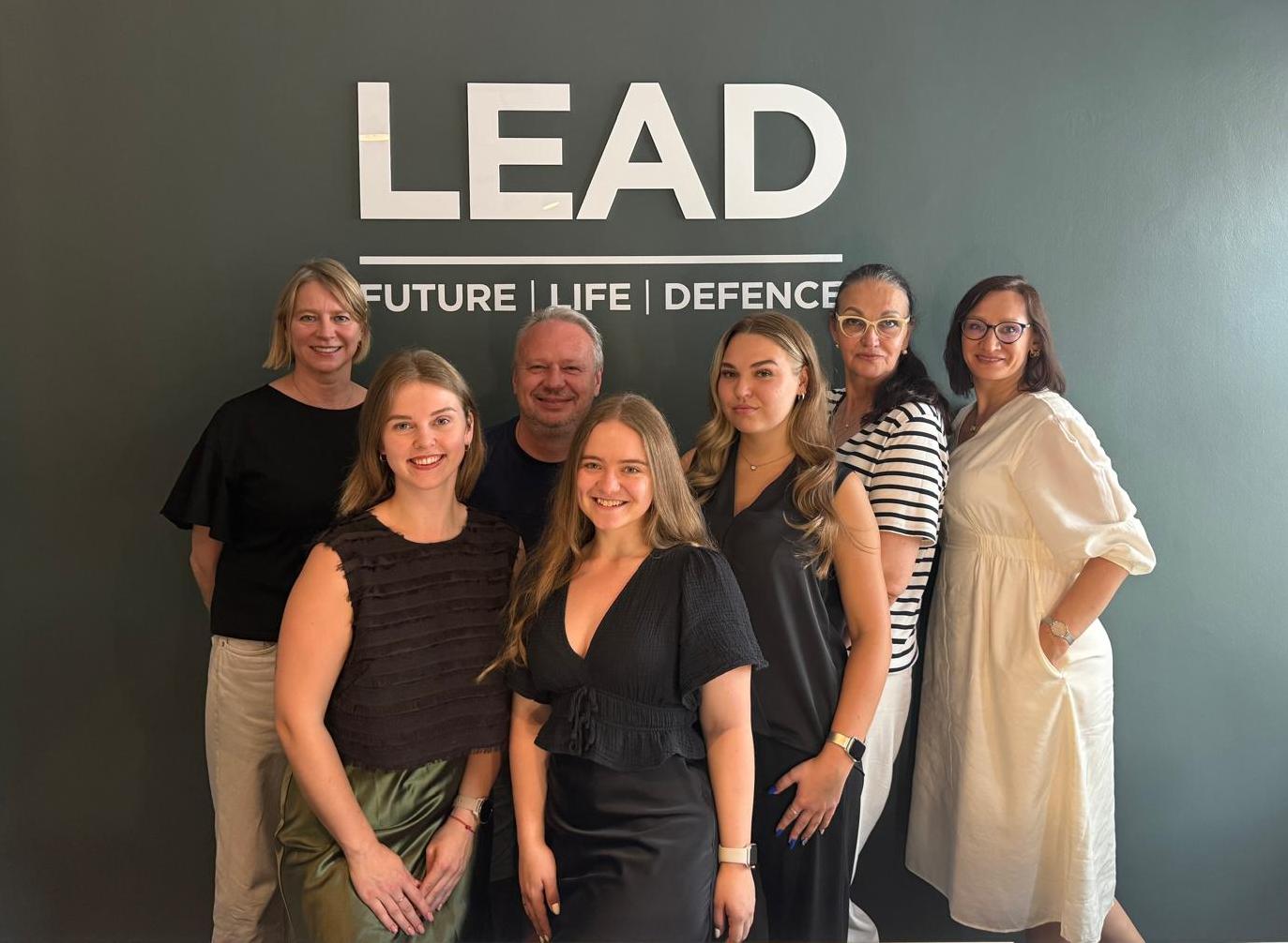 The agency team of LEAD in Latvia with their new logo in the background