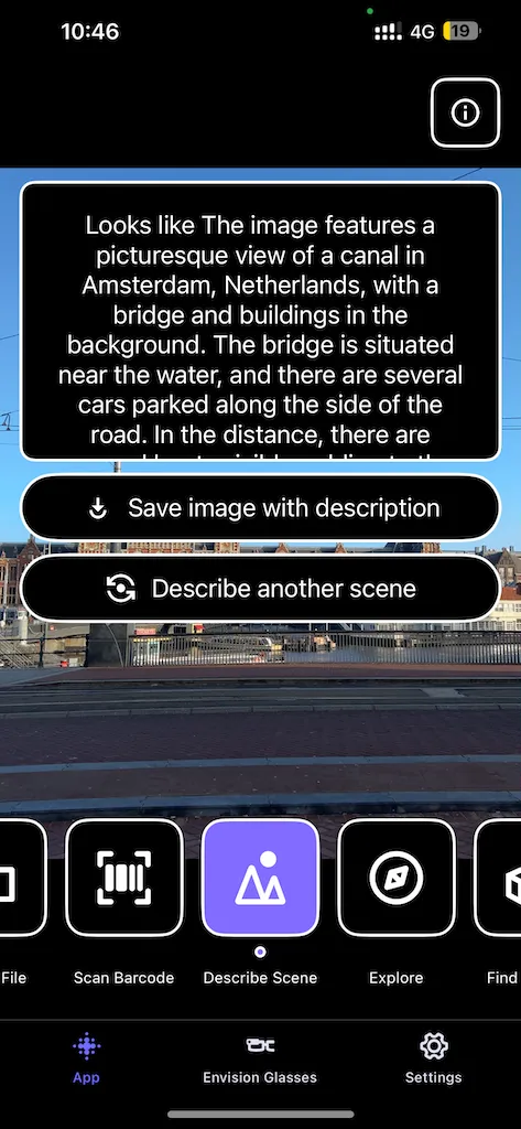 A screenshot of the Envision app's 'Describe Scene' feature, which has analyzed an image and provided a text description. The description reads, "The image features a picturesque view of a canal in Amsterdam, Netherlands, with a bridge and buildings in the background." The app's interface includes options to save the image with the description or describe another scene. Visible in the app's footer are additional functions like 'Scan Barcode', 'Explore', and 'Settings'. The actual scene, partially visible, shows a canal, a bridge, and the architecture of Amsterdam.