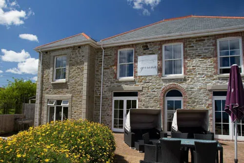 Charming stone-fronted hotel with a wide, accessible ramp leading to the entrance, surrounded by flowerbeds and outdoor seating