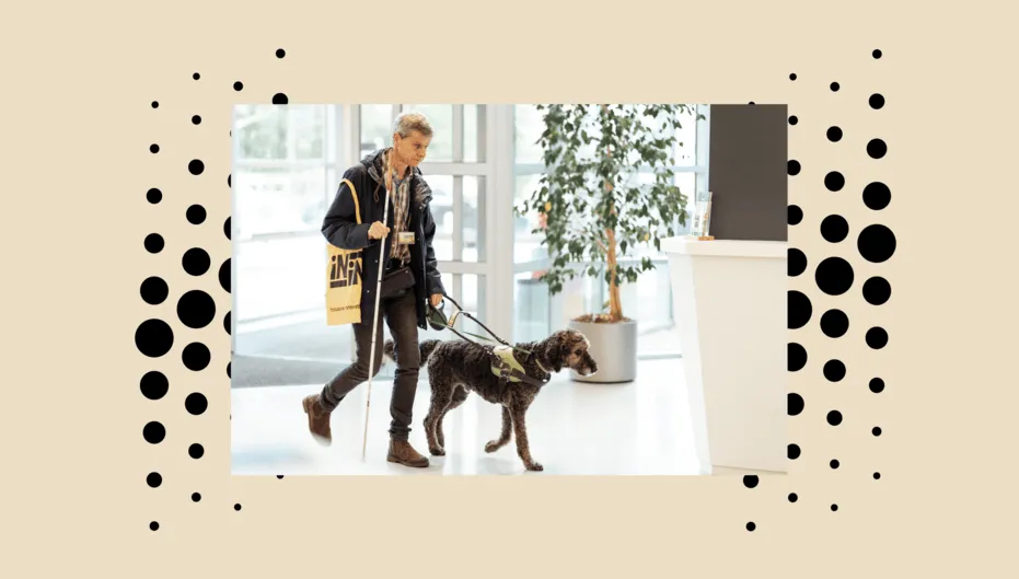 A person who is blind is holding his white cane, while also walking with his brown guide dog