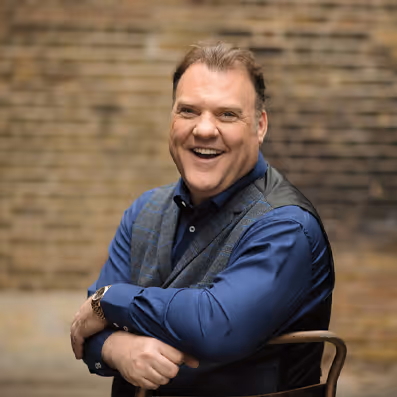Bryn Terfel sitting on a chair smiling