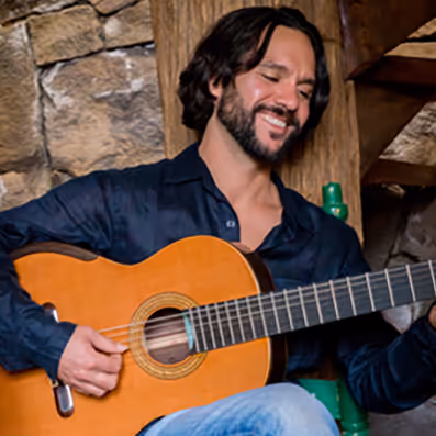 A man with a beard playing a guitar.