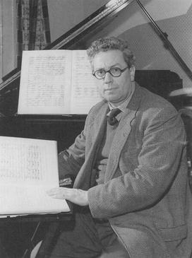 A man in a suit sitting at a piano.