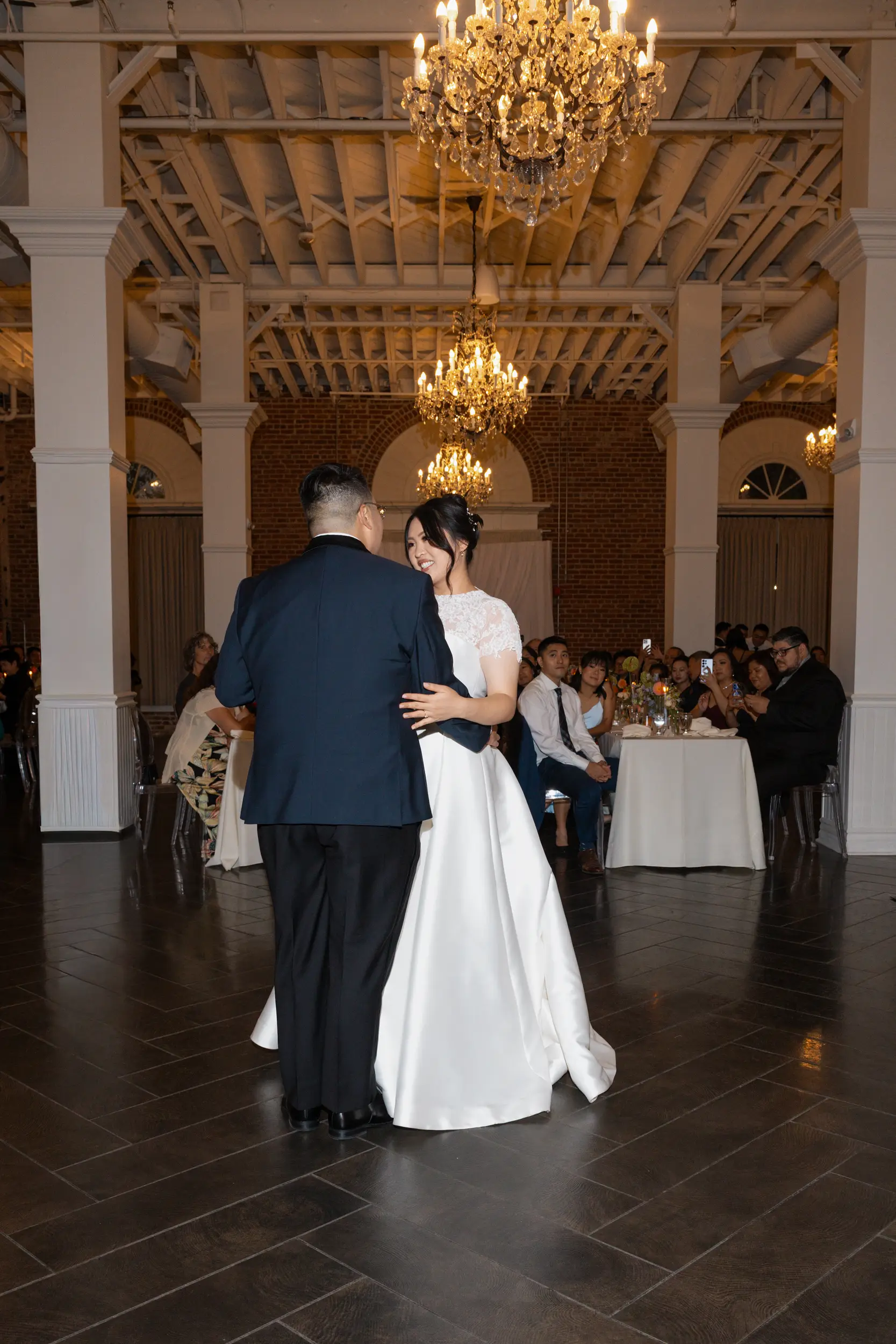 Bride and groom share first dance under sparkling chandeliers inside the Estate's Crystal Ballroom.