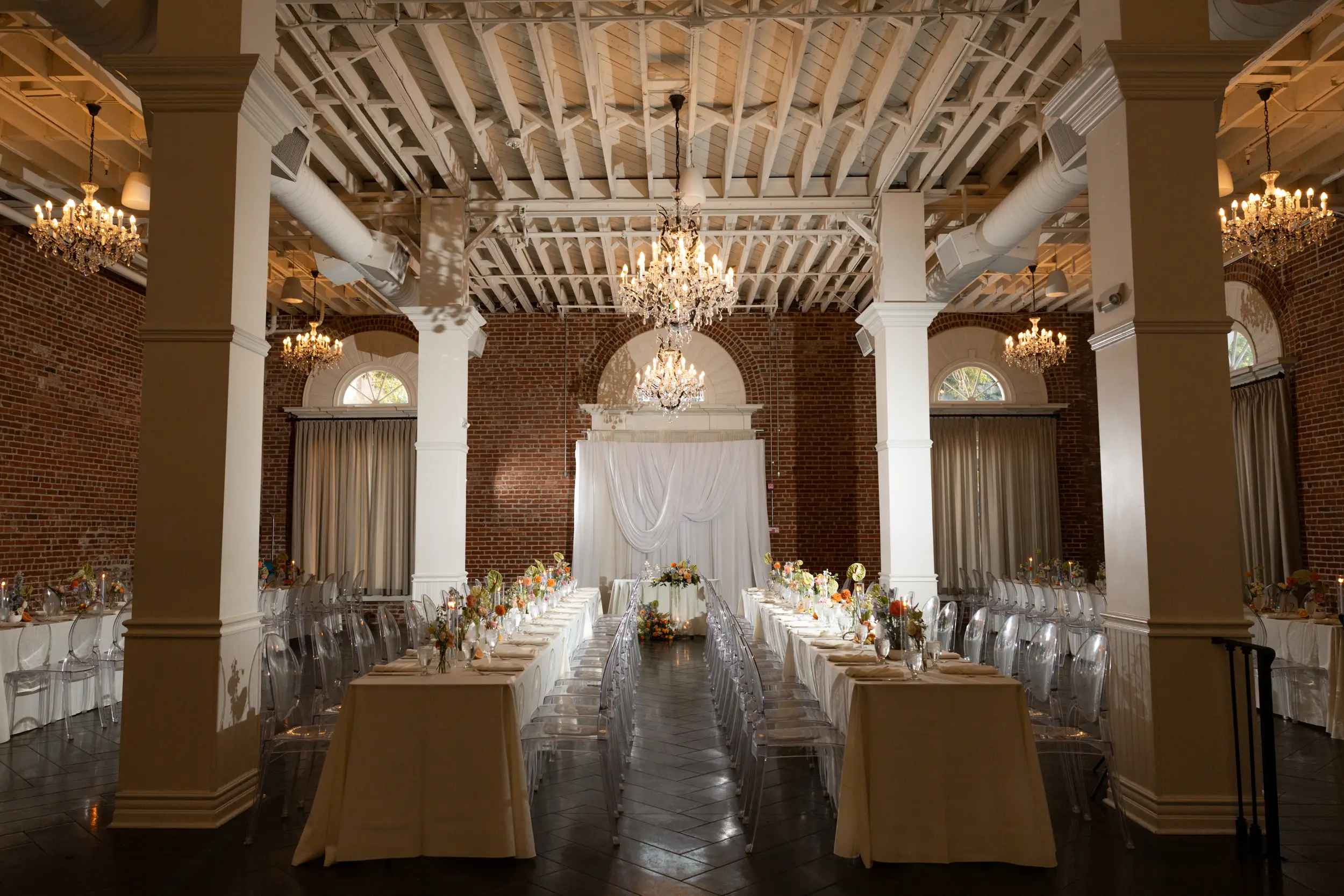 Colorful floral centerpieces sit atop reception tables inside the Crystal Ballroom with sparkling chandeliers hanging from the ceiling.
