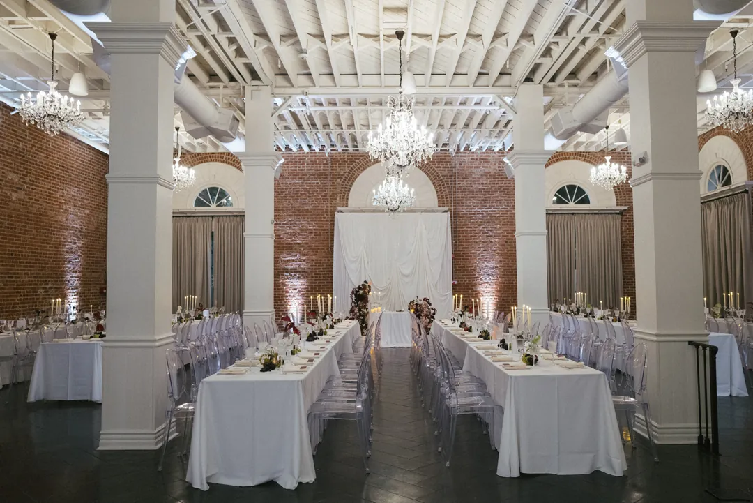 Reception tables arranged beneath ballroom chandeliers