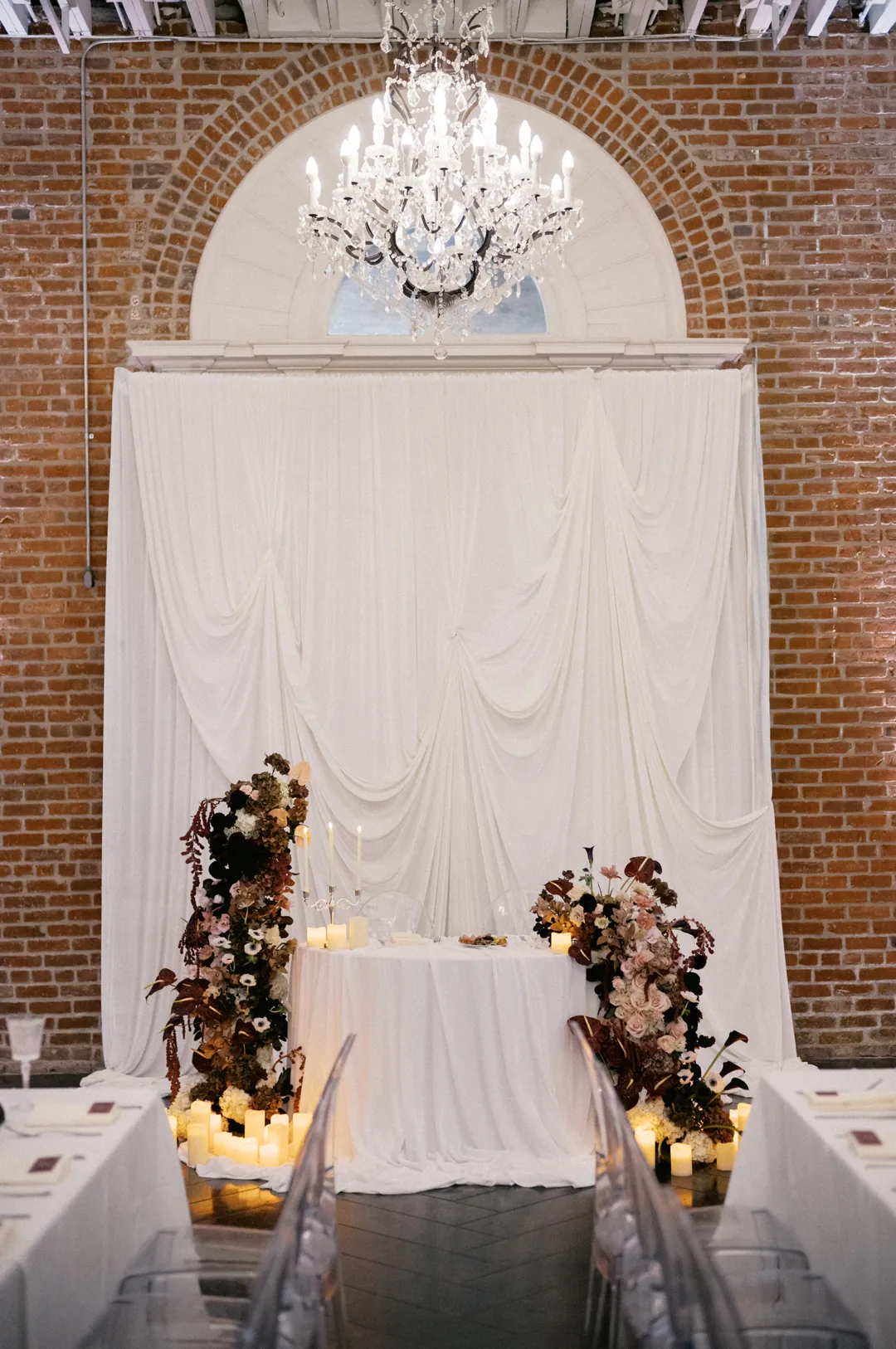 Sweetheart table in front of a white draped backdrop