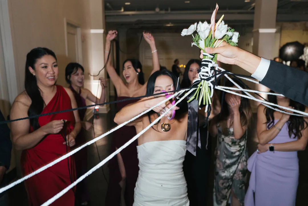 Guests holding ribbons attached to a bouquet
