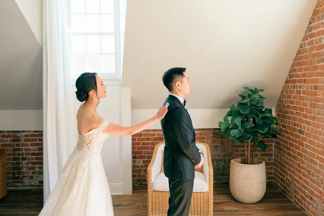 Bride approaching the groom from behind in a loft