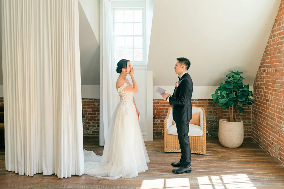 Couple standing apart beside a bright window