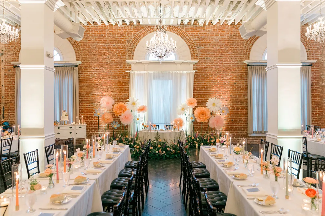 Long reception tables facing a colorful floral backdrop