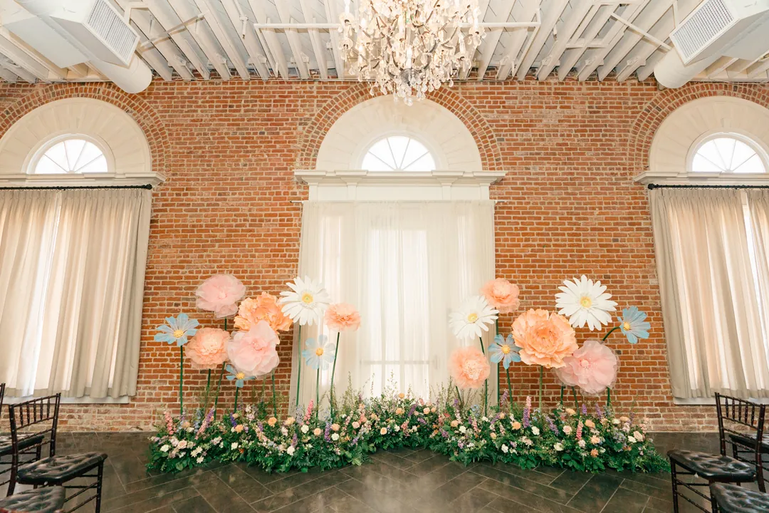 Large paper flowers decorating a ceremony backdrop