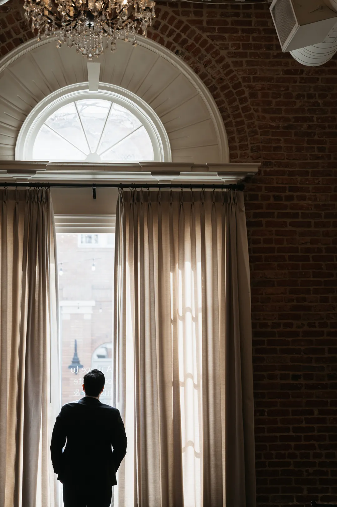 Silhouette of a guest beneath a tall arched window