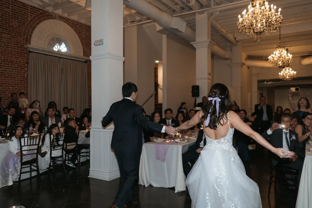 Couple entering their reception with arms outstretched