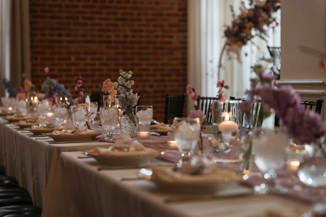 Long reception table decorated with candles and glassware