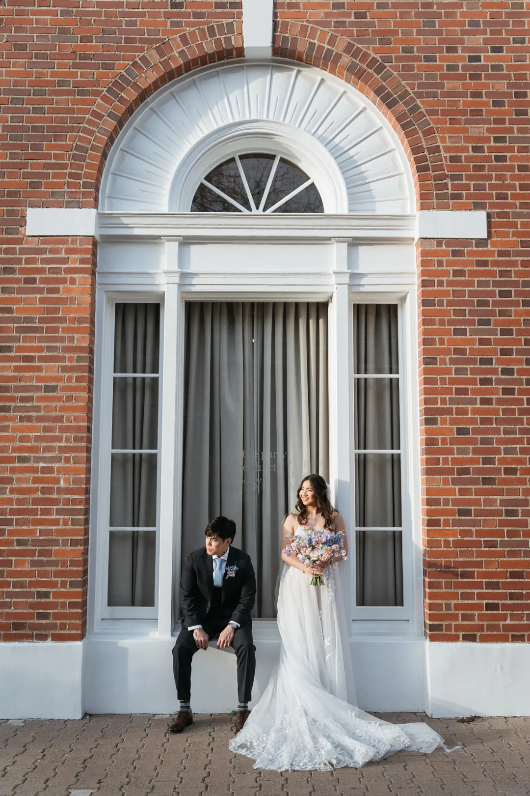 Couple posing beside a tall arched window
