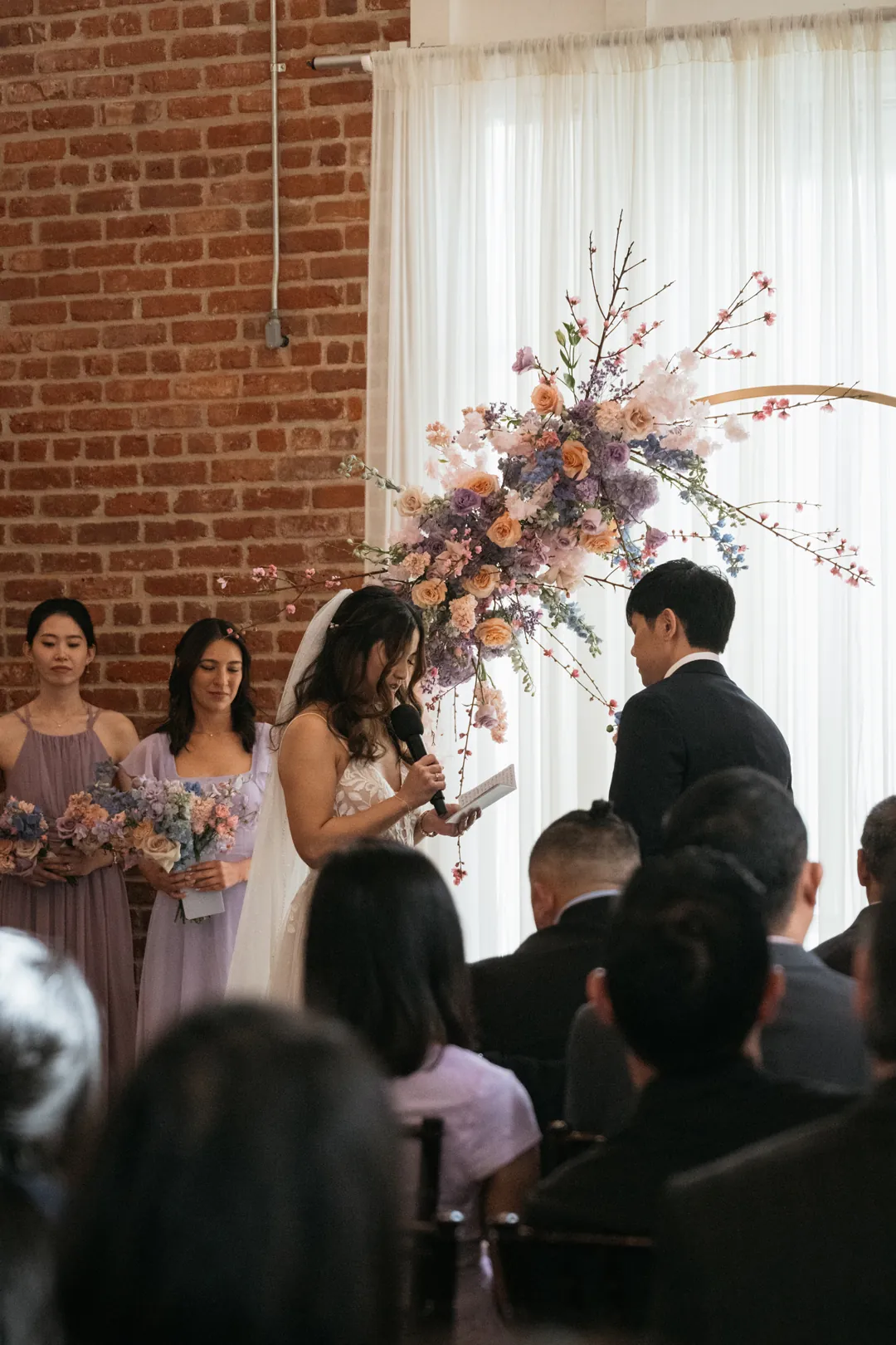 Couple exchanging vows beside a colorful floral arch