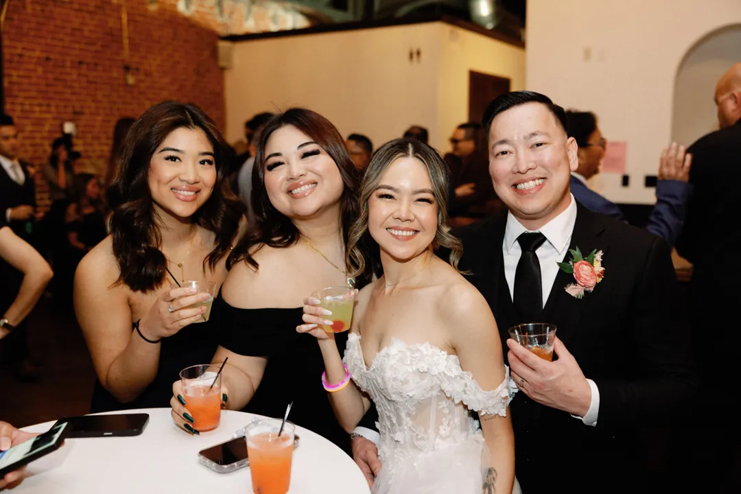 Newlyweds holding drinks with wedding guests