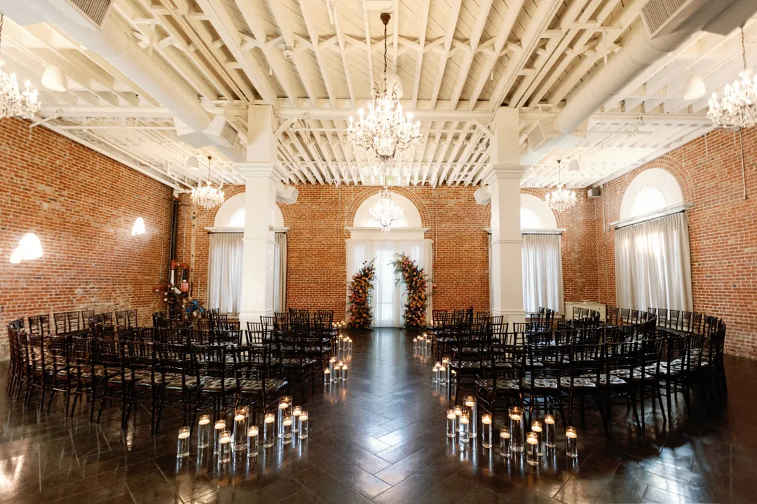 Empty ceremony chairs and candles beneath chandeliers