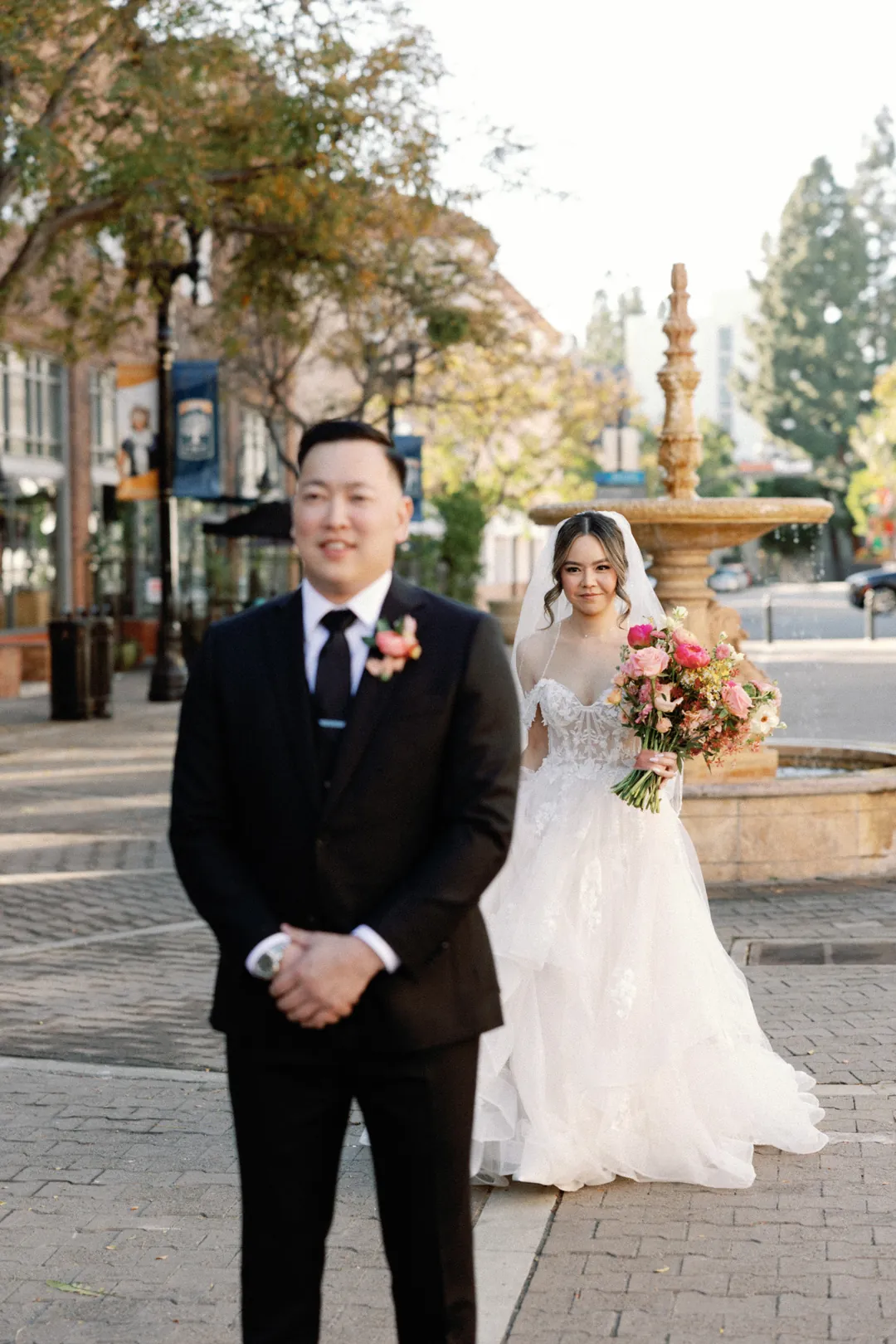 Bride approaching the groom from behind on a city street