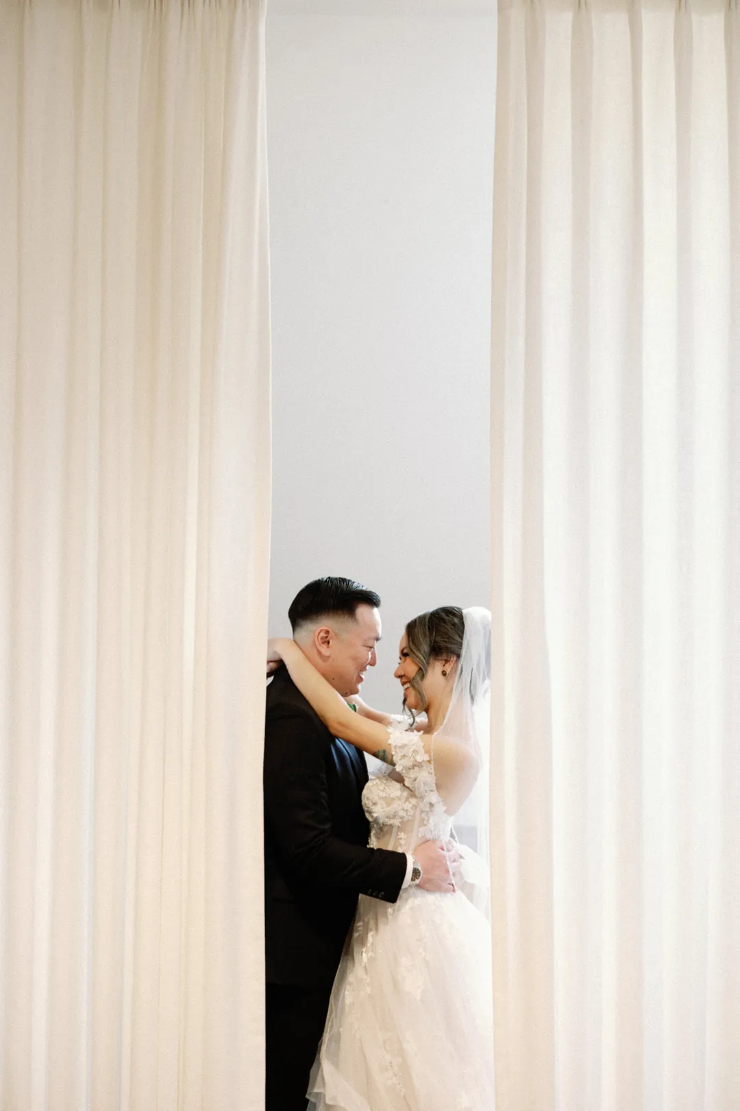 Couple kissing beside a bright curtain