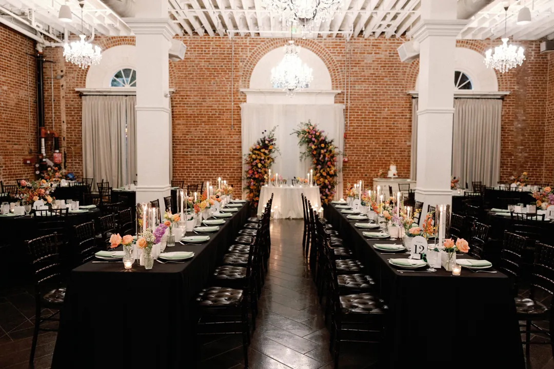 Long reception tables facing a floral backdrop