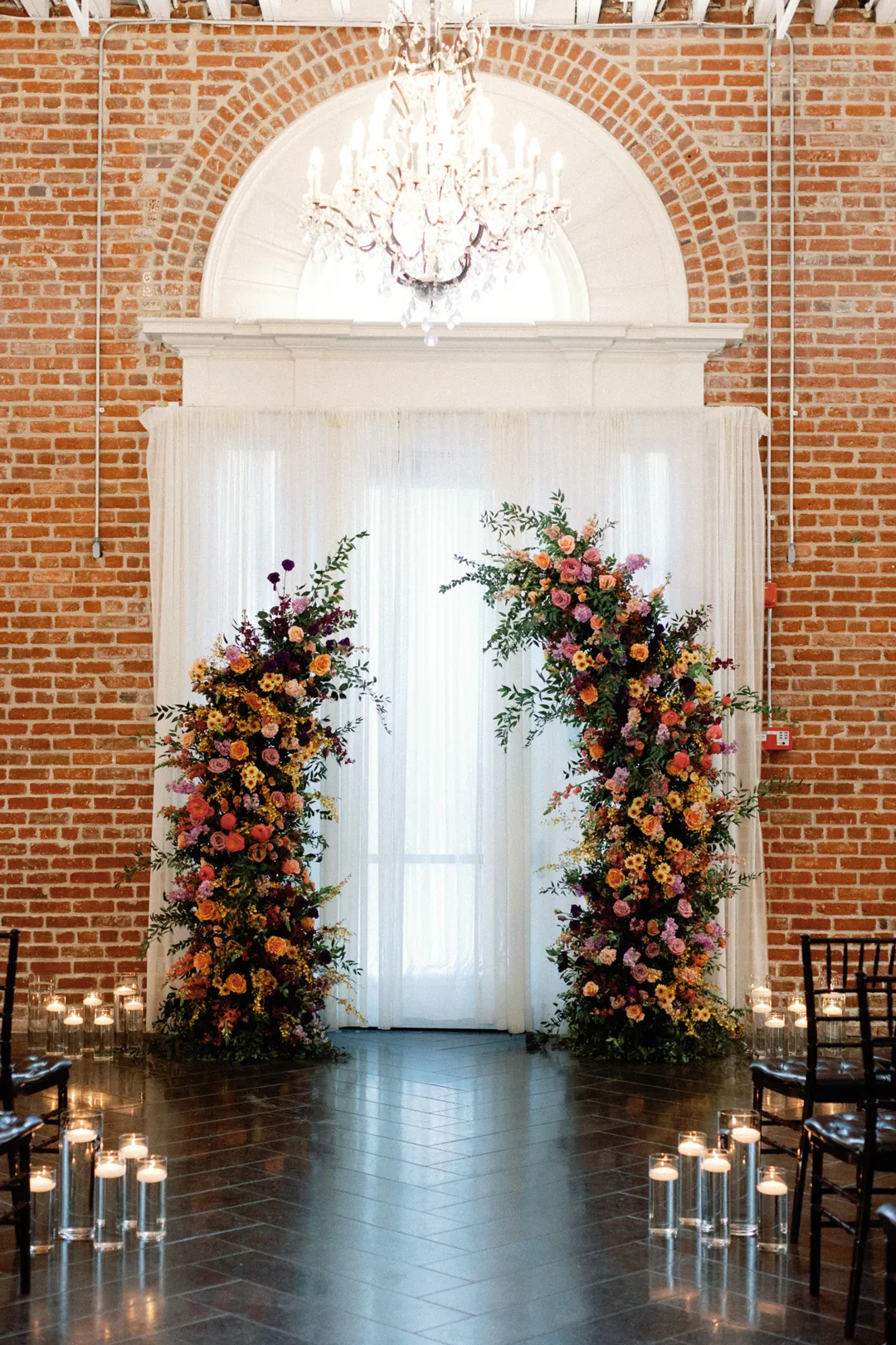 Floral ceremony arrangements beneath an arched window