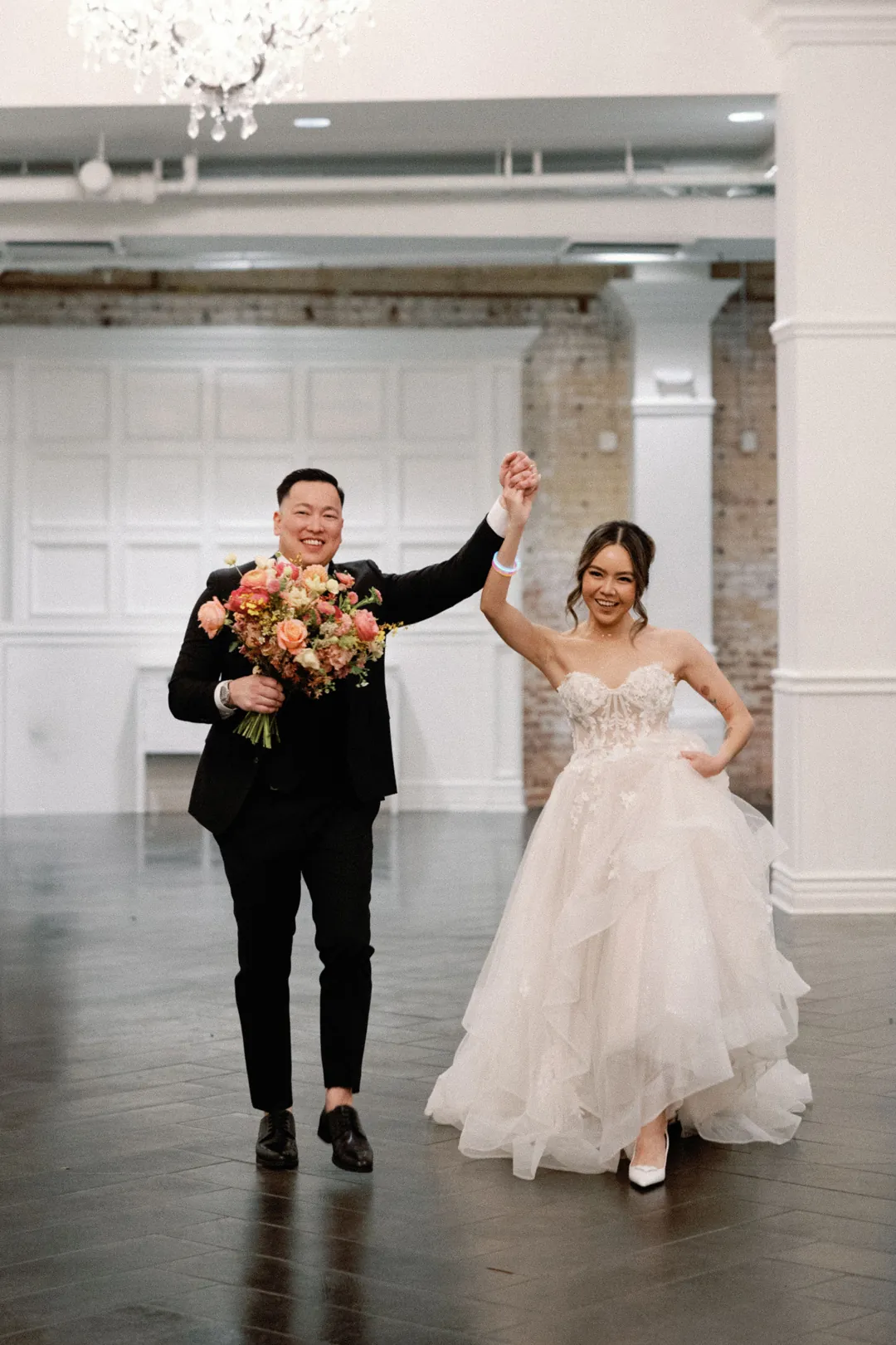 Newlyweds entering the reception with raised hands