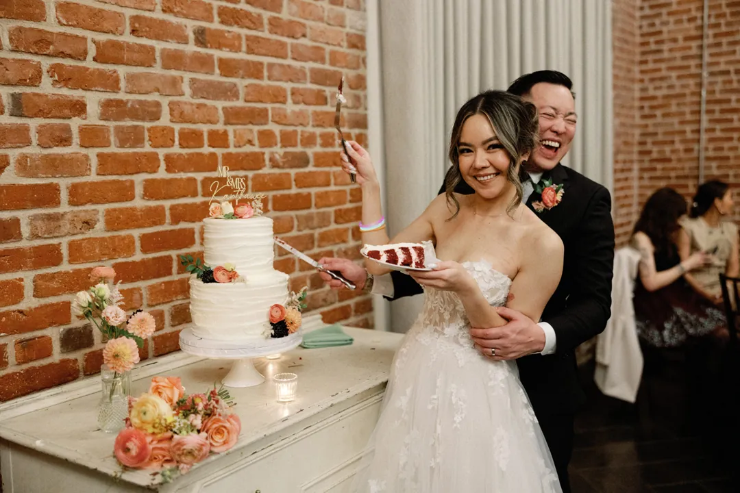 Couple laughing while cutting their wedding cake