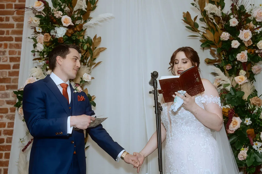 Bride reading vows while holding the groom's hand
