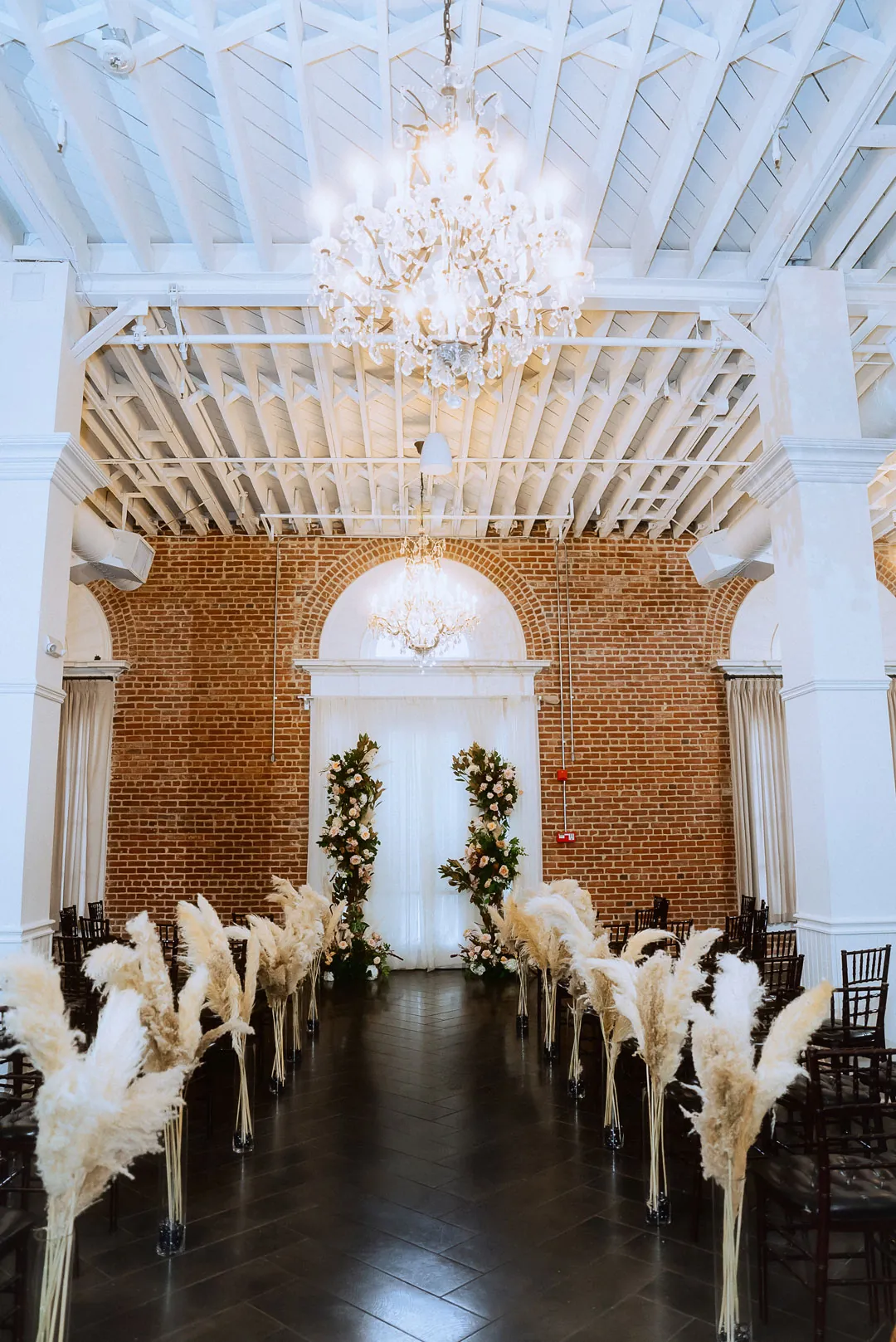 Ceremony aisle lined with white flowers beneath chandeliers