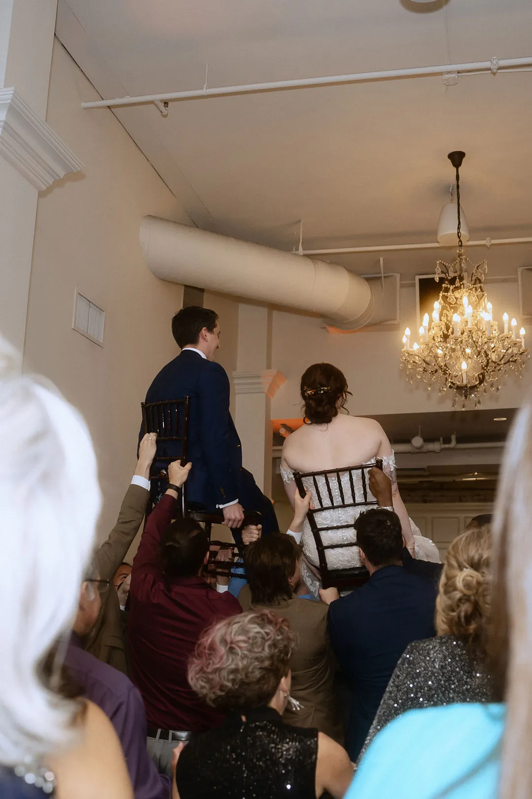 Bride and groom being lifted above wedding guests