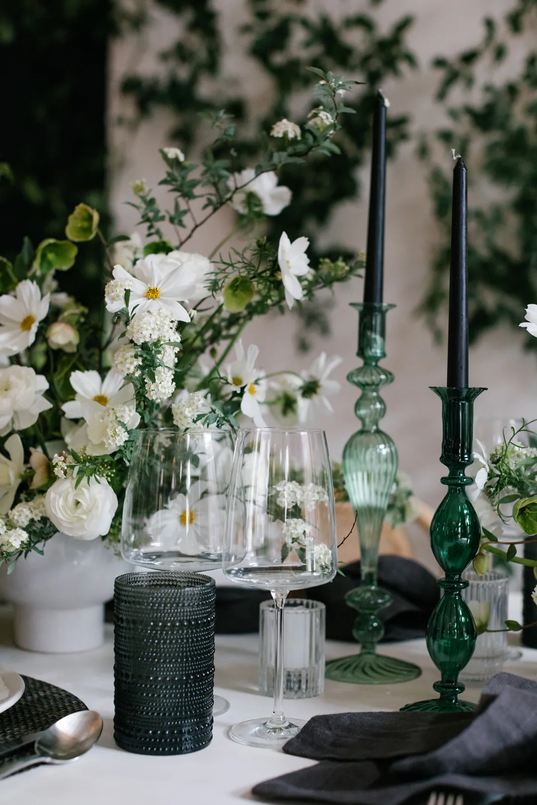 White flowers and dark green glassware on a dining table