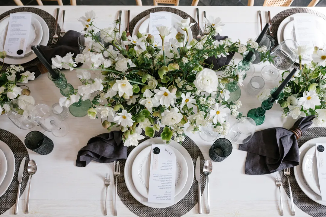 Overhead view of a reception table with white flowers and dark place settings