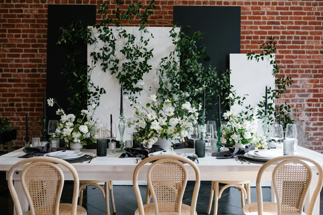Reception table with woven chairs and green floral decorations