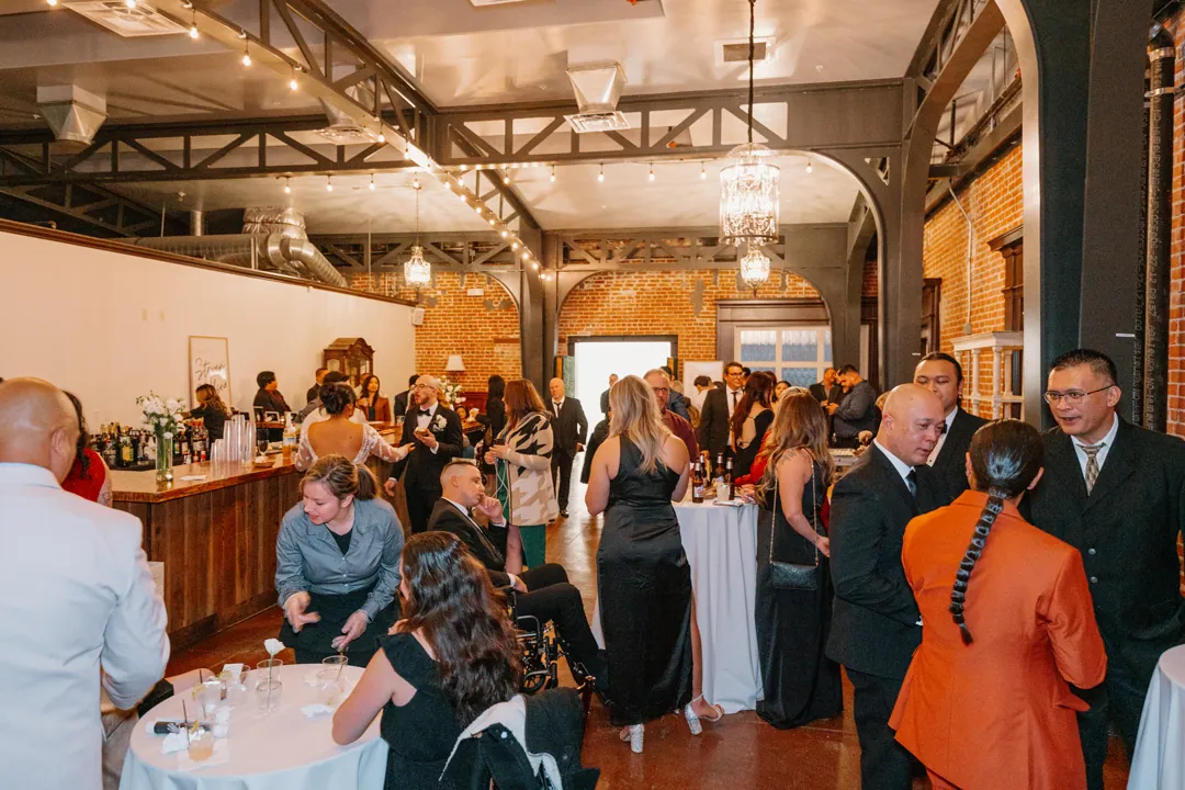 Guests mingling beneath chandeliers in a cocktail reception room