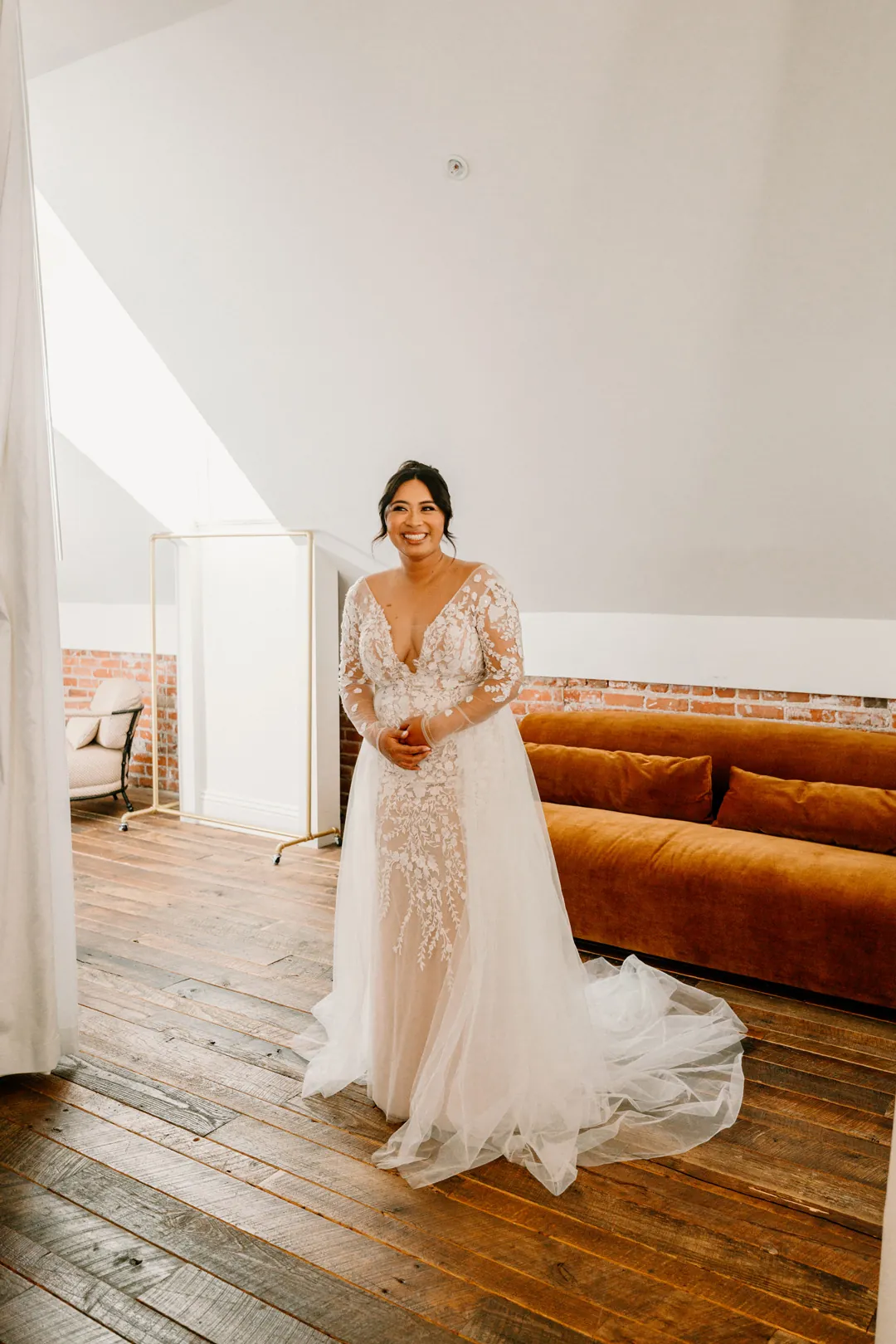Bride smiling beneath a sloped ceiling in a bright lounge
