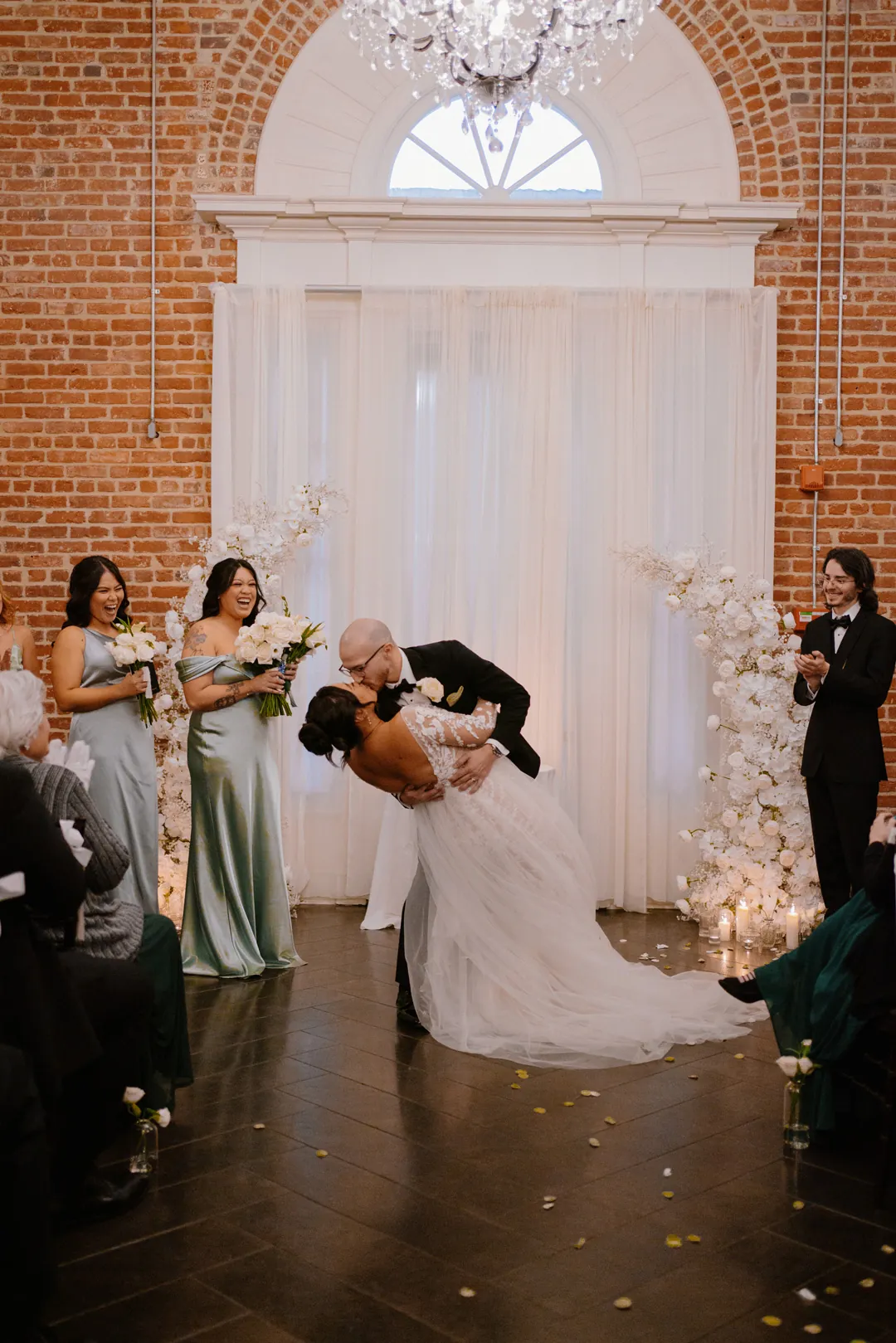Couple kissing before pale ceremony drapes