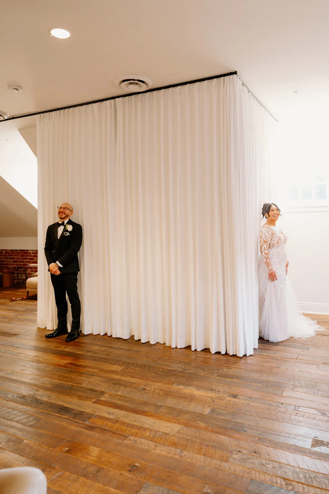 Couple facing one another before pale room curtains