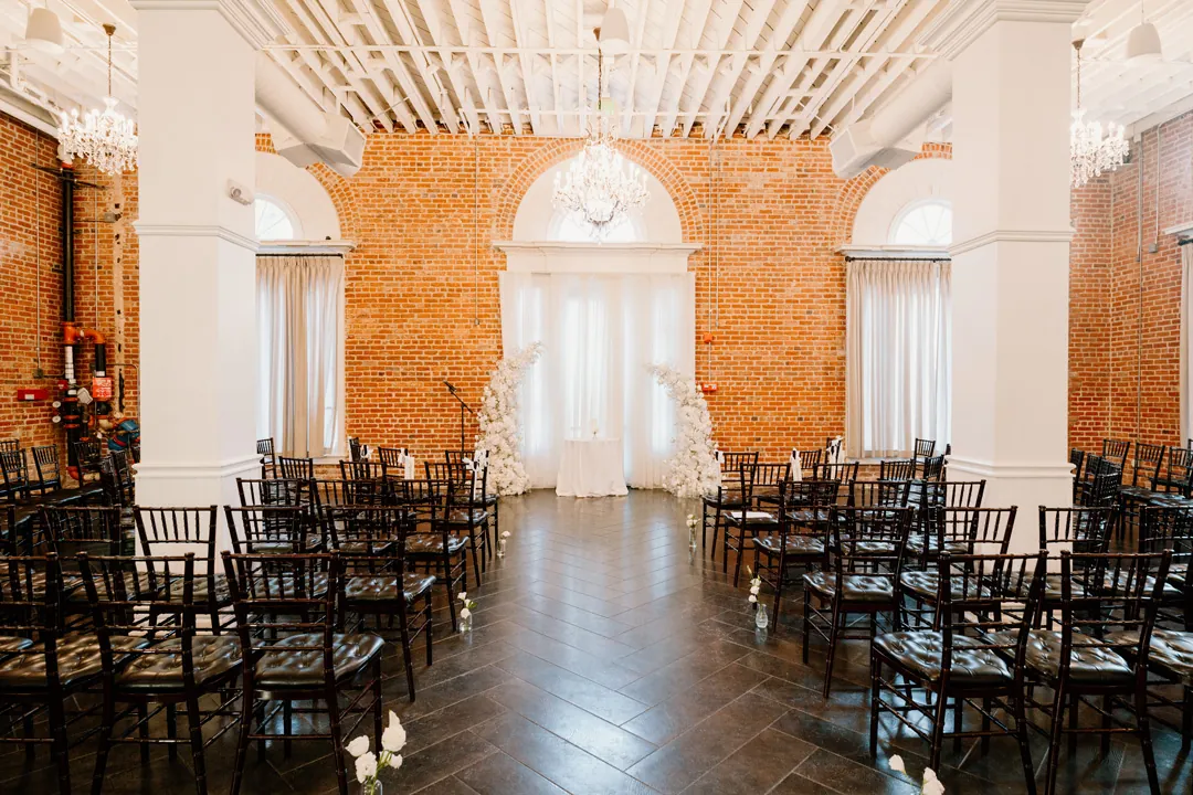 Rows of black ceremony chairs in a bright brick-walled hall