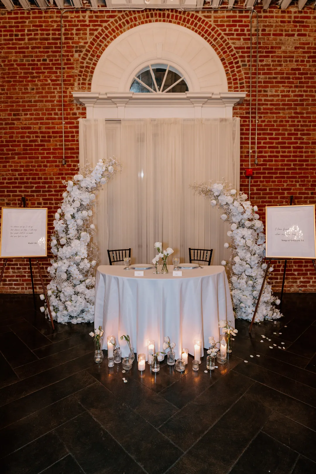 Round sweetheart table beneath an arched window