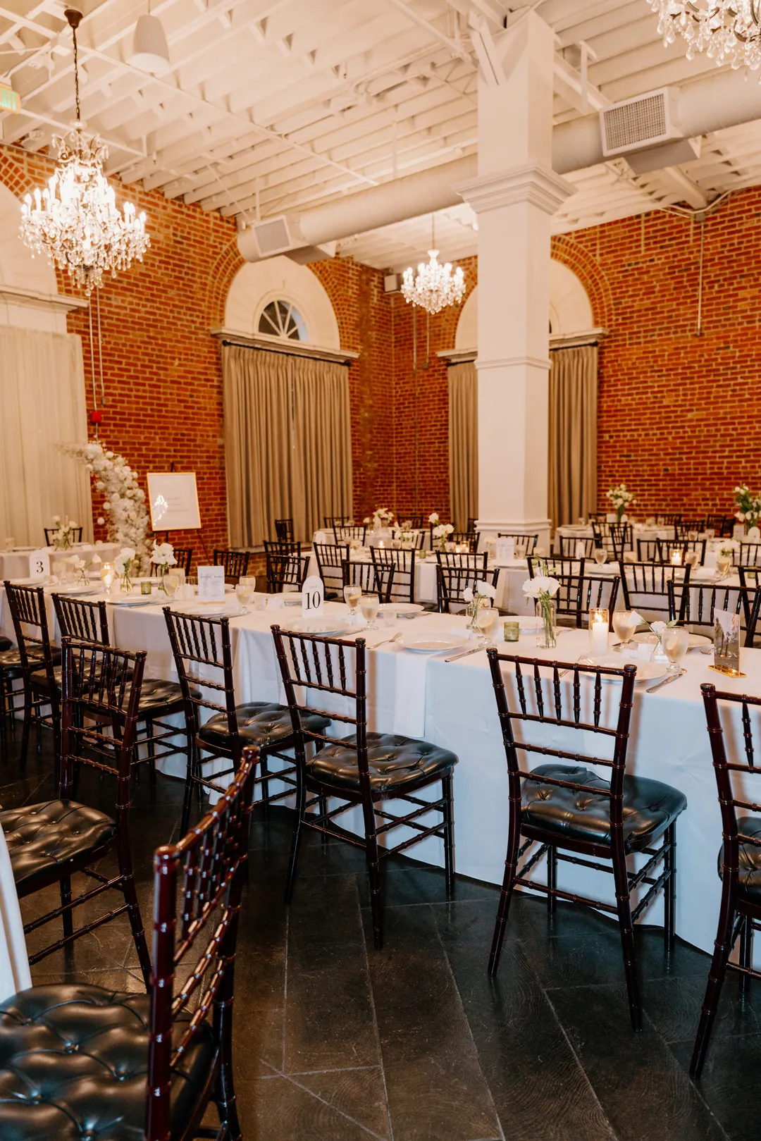 Place settings lining long tables beside tall arched windows