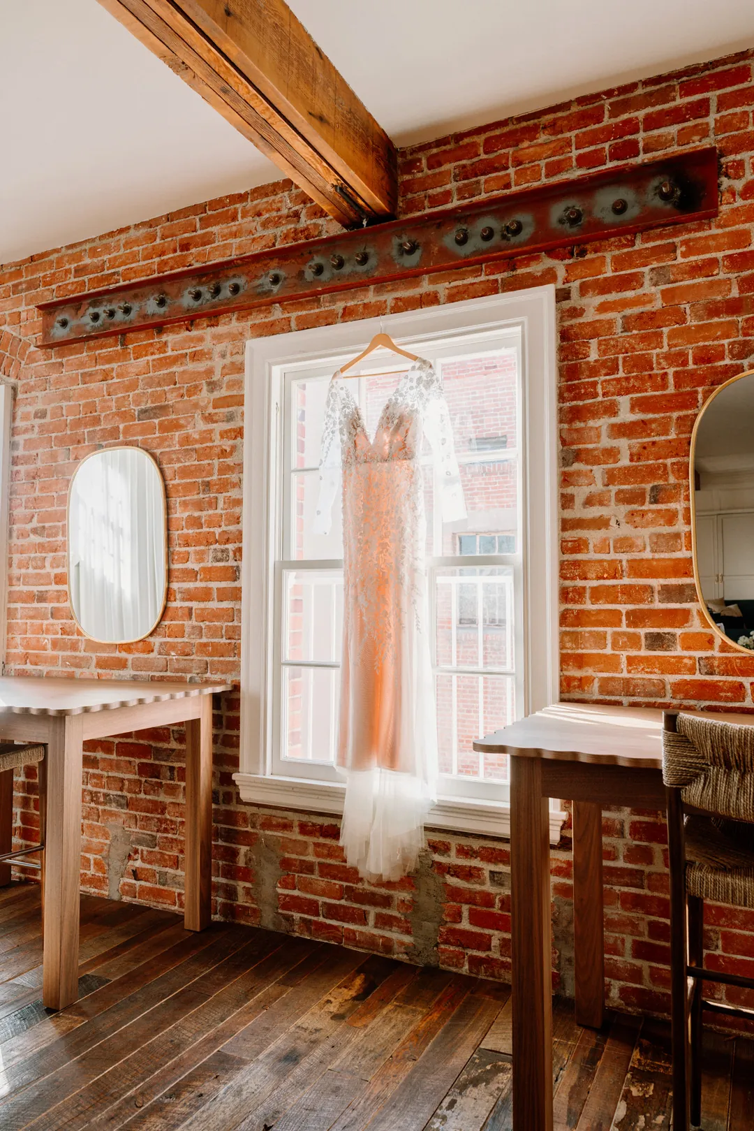 Wedding dress hanging before a window in a brick wall