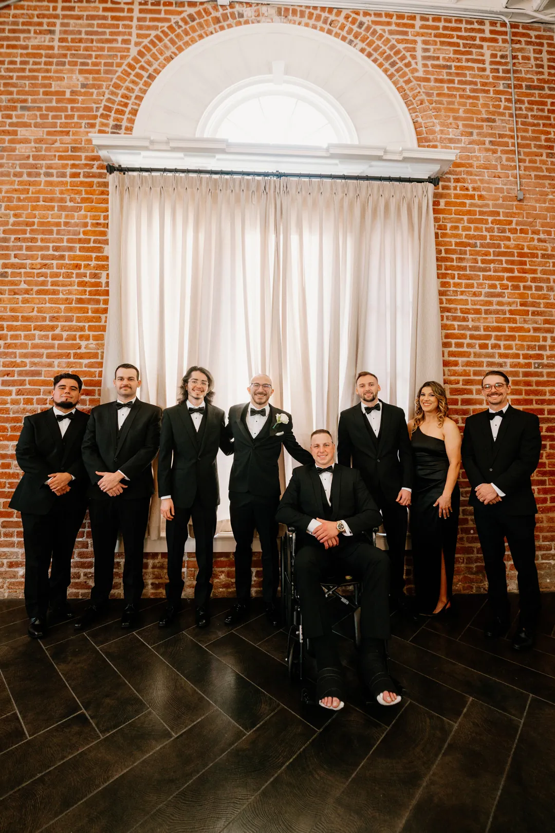 Groomsmen standing beneath a large arched window
