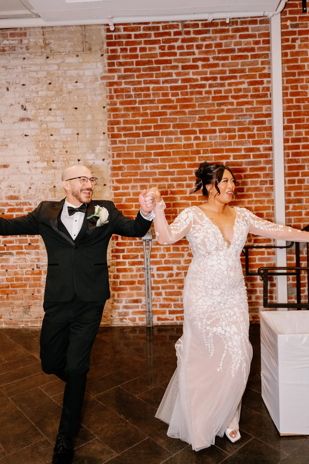 Couple entering their reception with arms outstretched