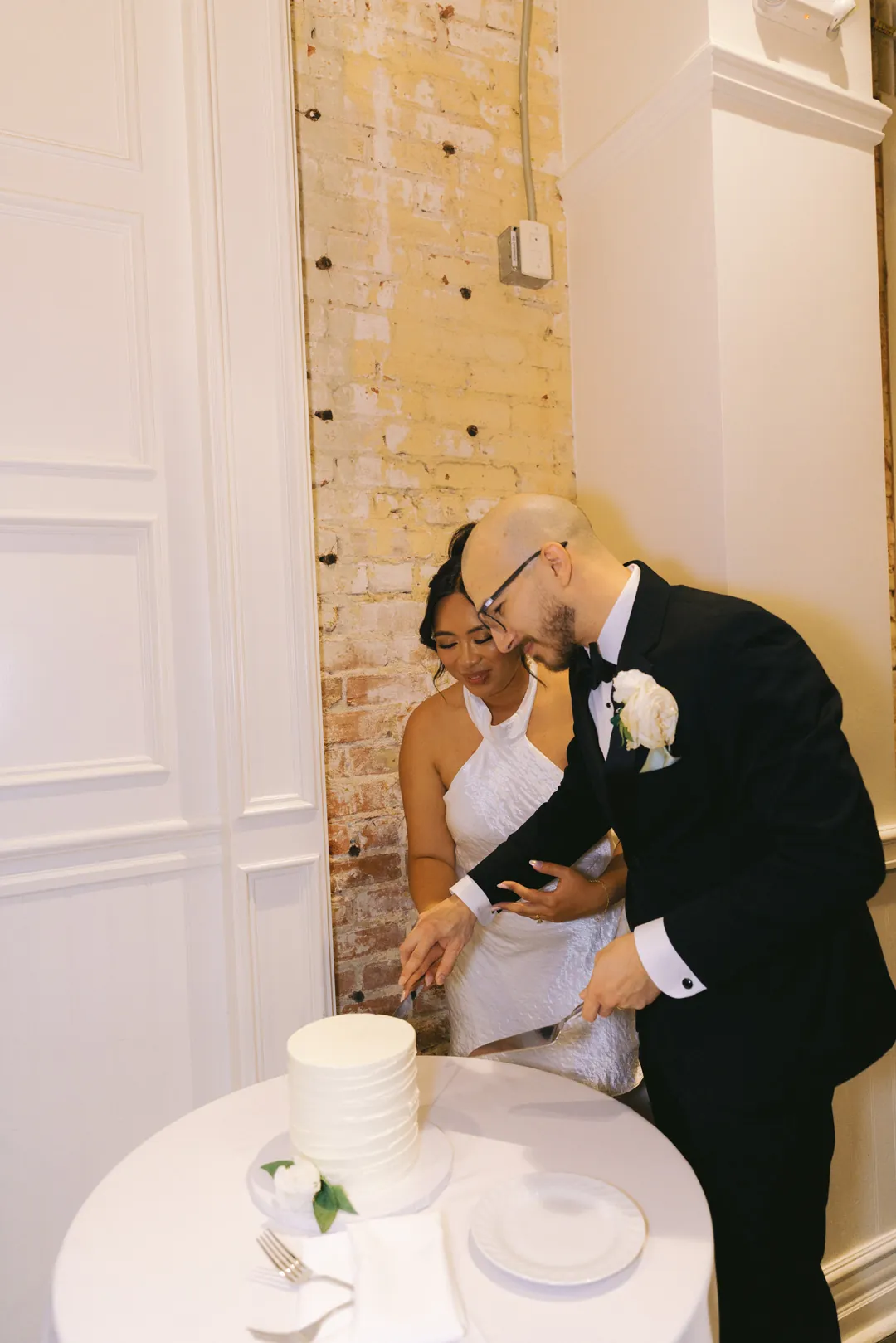 Couple cutting a small white wedding cake together