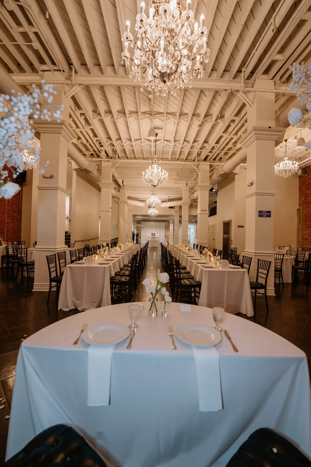 View along long reception tables beneath a white beamed ceiling