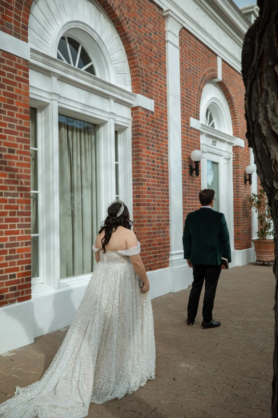 Bride approaching the groom outside a brick building