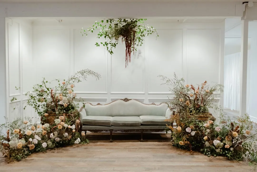 Floral arrangements surrounding a sofa in a bright room