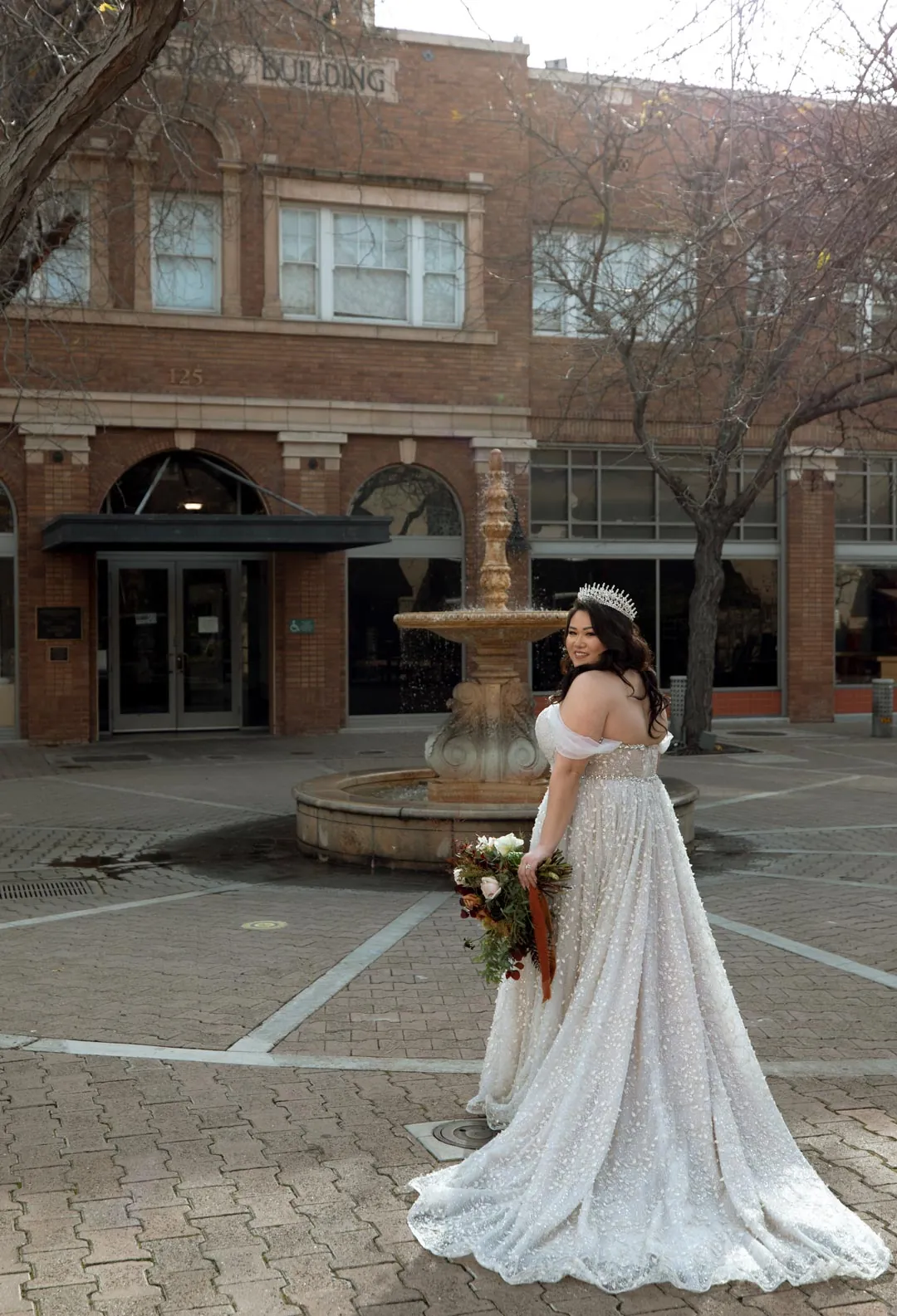 Bride holding a bouquet beside an outdoor fountain